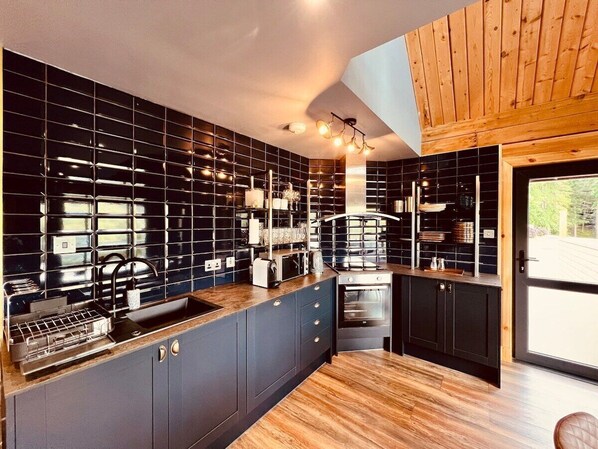 A modern kitchen with black tiled backsplash, wooden cabinets, and a built-in oven.