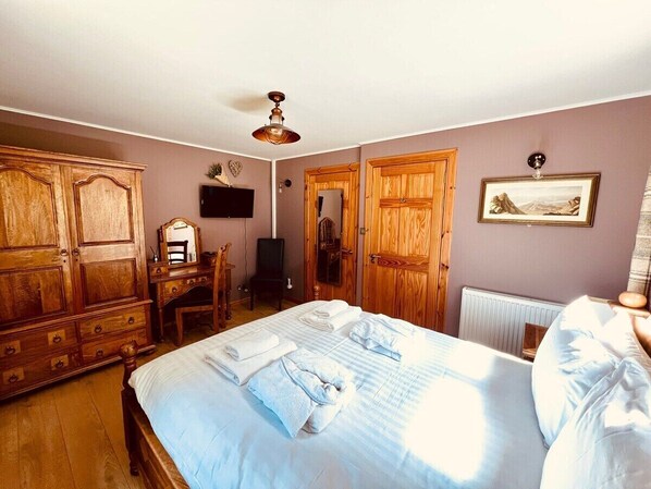 A bedroom with a bed, wooden wardrobe, a desk, and a radiator. - Group lodge with hot tub and fire pit (Inverness)