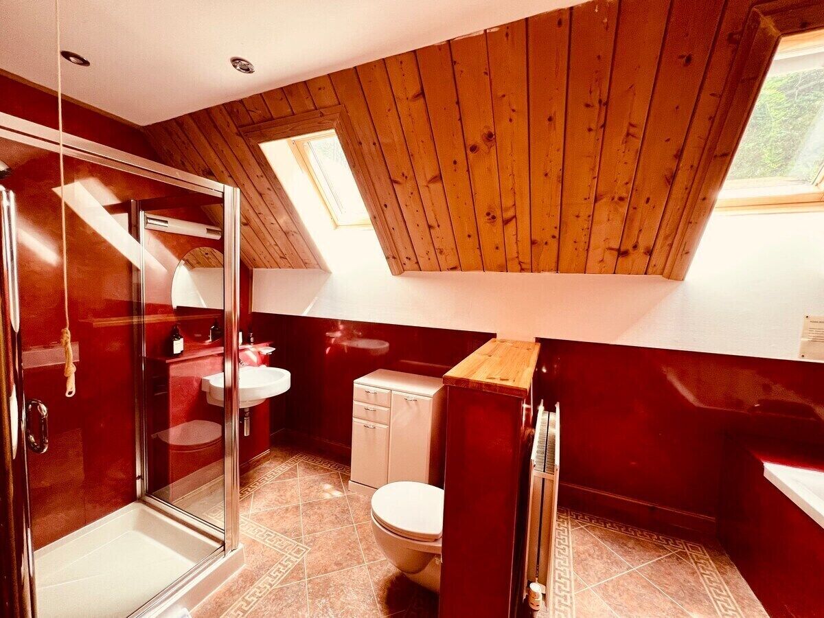 A compact, modern bathroom with a glass shower enclosure, a white toilet, and a small sink.