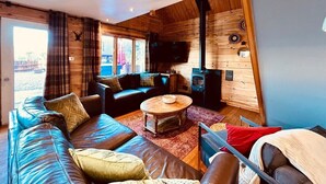 A cozy cabin interior with a wooden interior, a sofa, a coffee table, and a fireplace. - Group lodge with hot tub and fire pit (Inverness)