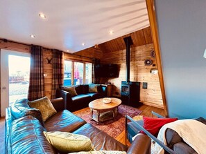 A cozy cabin interior with a wooden interior, a sofa, a coffee table, and a fireplace.