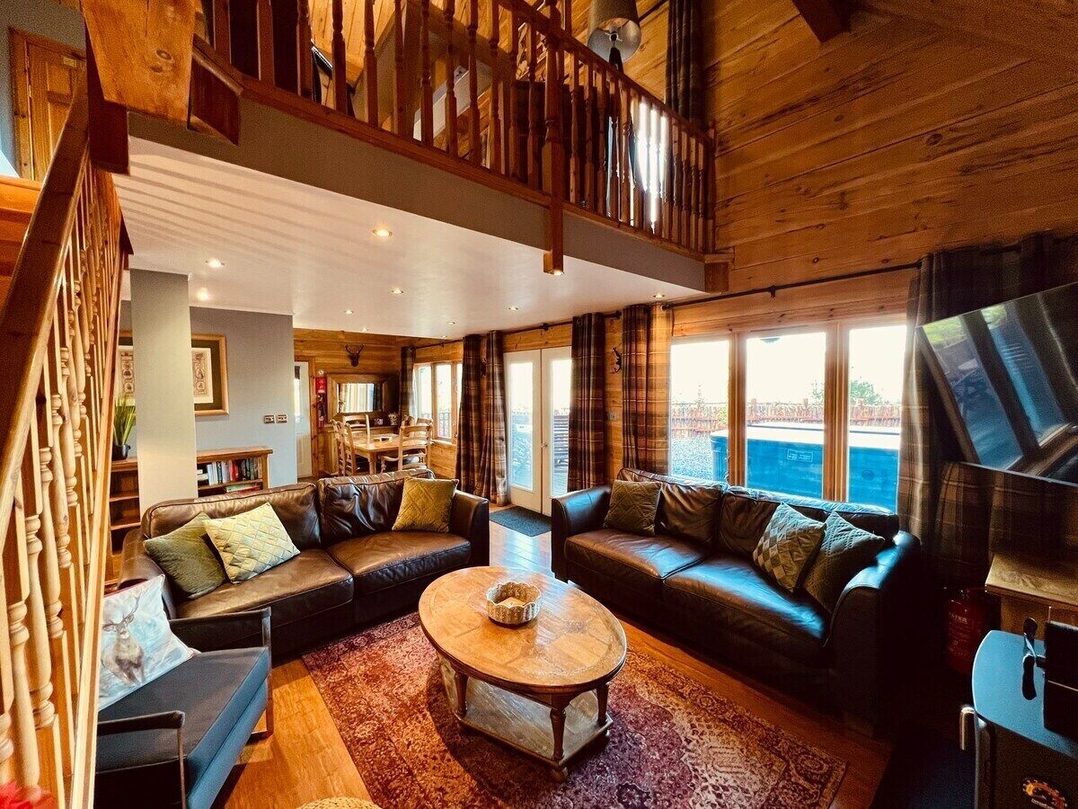 A spacious living room with a large sectional sofa, a coffee table, and a view of the outdoors through large windows.