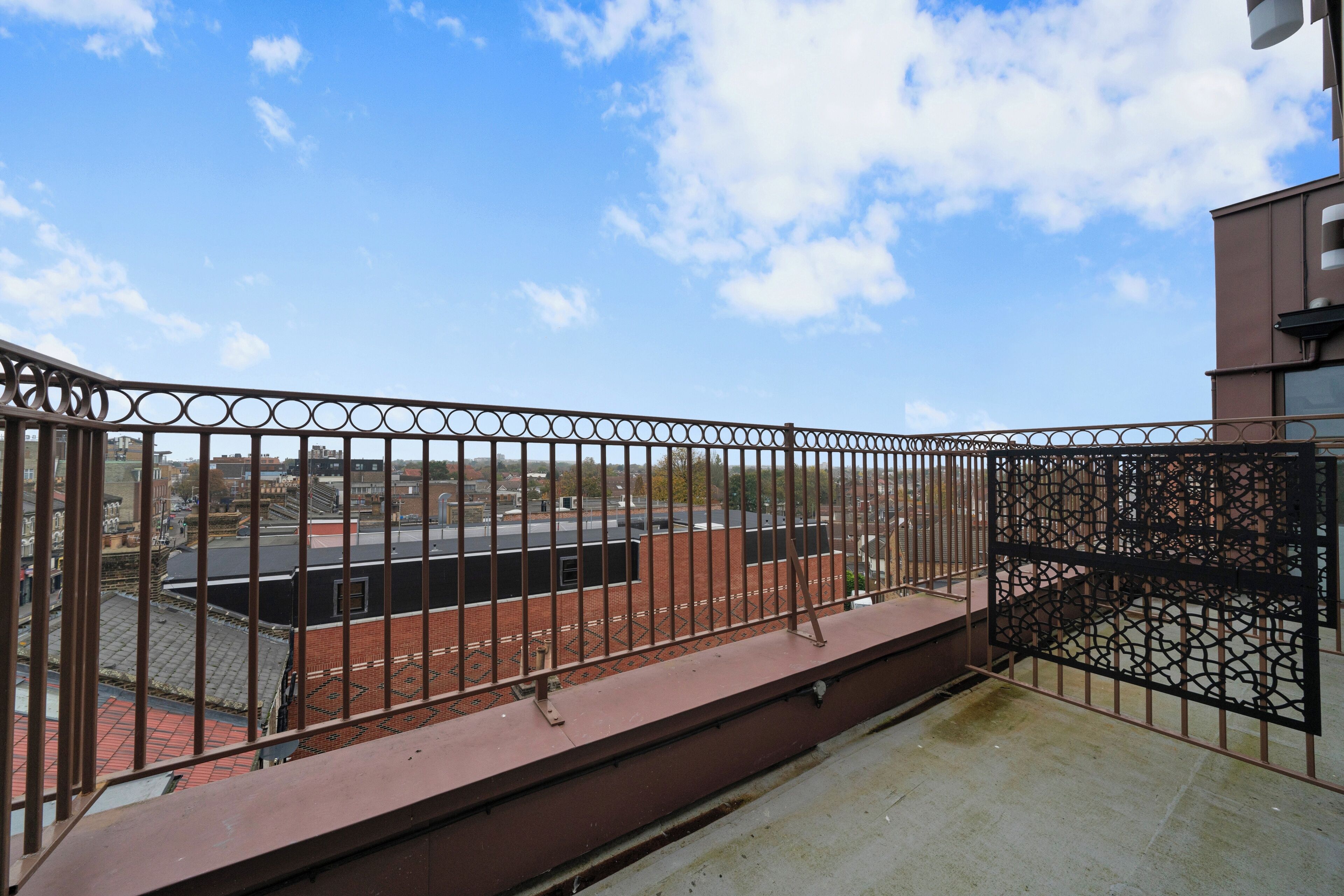 A balcony with a metal railing overlooking a cityscape.