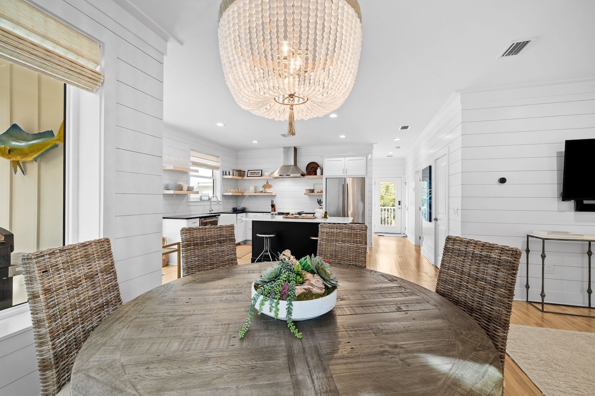 A modern kitchen with white cabinetry, a stainless steel refrigerator, and a hanging chandelier.