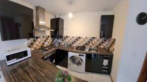 A compact kitchen with a microwave, stove, sink, and washing machine.