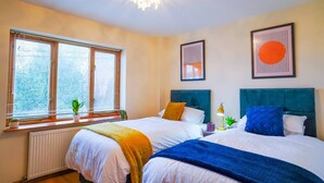 A hotel room with two beds, a radiator, a window with blinds, and wall art.