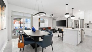 A modern kitchen with white cabinets, a large island, and a dining area with a round table and chairs.