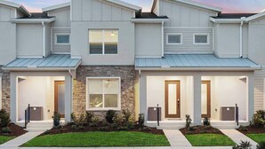 A modern two-story townhouse with a stone facade, large windows, and a well-maintained lawn. - Wendy's Wing | Gorge Villa w/ Pirate BR, Grand Suites & PVT Pool - Near Airport (Orlando)