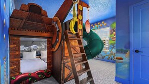 Un área de juegos infantiles con un tobogán, una escalera y una cama.