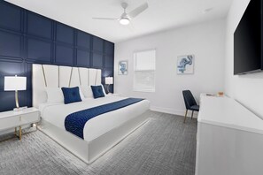 Een moderne slaapkamer met een groot bed, een bureau en een plafondventilator.