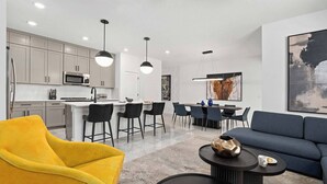 Una sala de estar moderna con un sillón amarillo, un sofá azul y una mesa de centro con un jarrón decorativo.