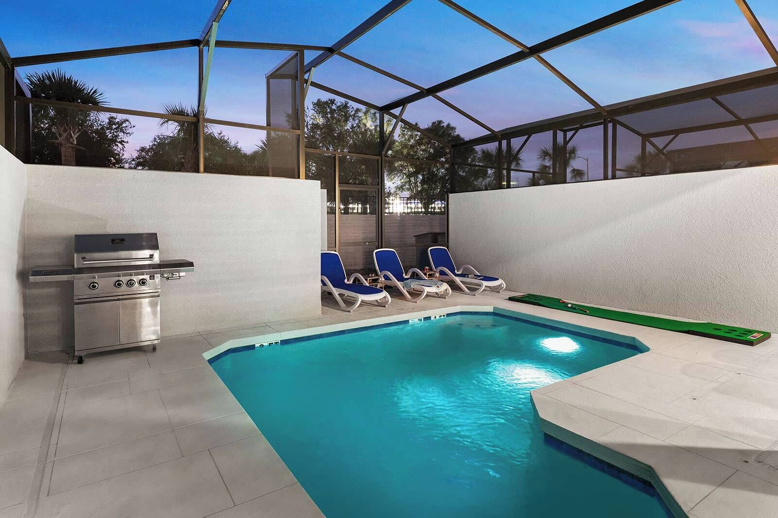 An outdoor swimming pool with lounge chairs and a barbecue grill.