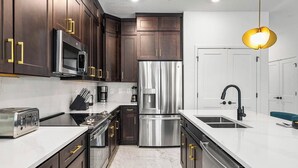 Una cocina moderna con armarios de madera oscura, electrodomésticos de acero inoxidable y encimera blanca.