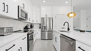 Una cocina moderna con armarios blancos, electrodomésticos de acero inoxidable y una isla central con lavamanos.