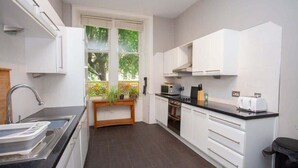 A modern kitchen with white cabinets, a black countertop, and a window with a view of greenery.