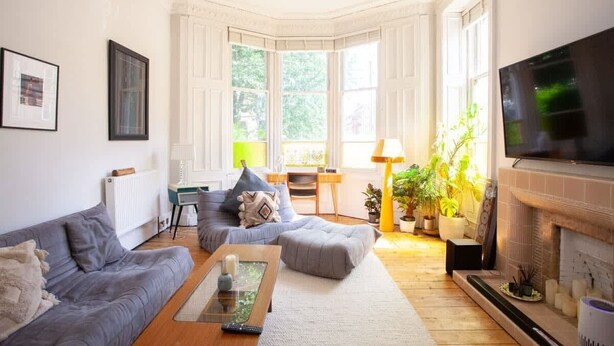 A living room with a grey sofa, a coffee table, a fireplace, and a TV mounted on the wall.
