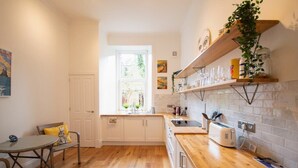 Eine Küche mit weißen Schränken, einer Holz Arbeitsplatte, einem Fenster und einem Essbereich mit Tisch und Stühlen.
