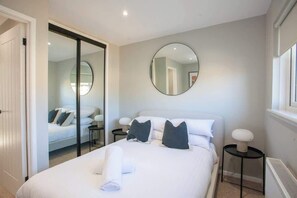 Ein modernes Hotelzimmer mit einem Bett, einem runden Spiegel, einem Nachttisch und einer Heizung.