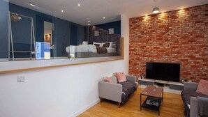 A modern living room with a large mirror, a TV, and two sofas. - Stunning City Centre Duplex (Glasgow City)