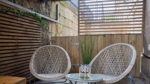 A patio area with two wicker chairs and a small table, a wooden bench, and a green mat. - West End Flat with Private Terrace Glasgow (Glasgow City)