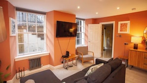 A living room with a sofa, a chair, a TV, and a radiator. - West End Flat with Private Terrace Glasgow (Glasgow City)