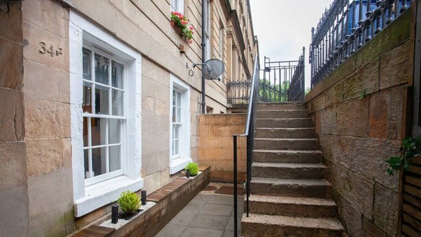 A narrow alleyway with a set of stone steps leading up to a gated entrance. - West End Flat with Private Terrace Glasgow (Glasgow City)