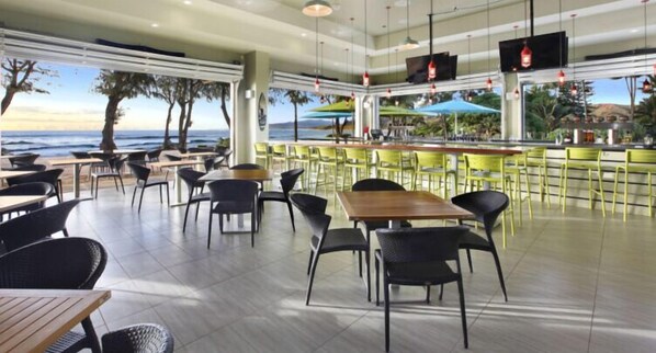 A restaurant with outdoor seating, a bar area, and large windows offering ocean views. - Lae Nani Ala Kukui A/C Ground floor Oceanfront (Kapaa)