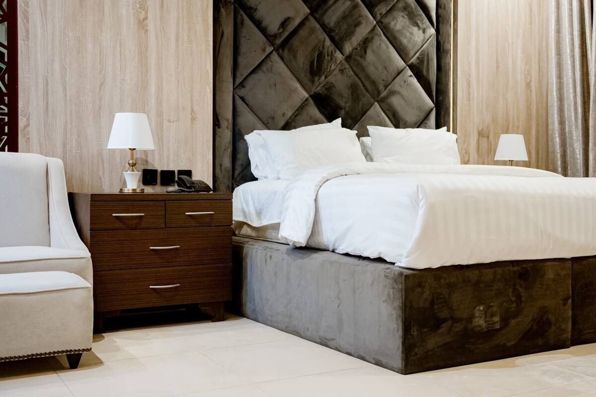 A modern bedroom with a large bed, a bedside table with a lamp, and a chair.