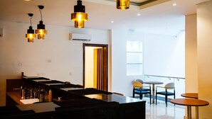 A modern kitchen with a central island, overhead pendant lighting, and a view of the balcony area with seating. - Summit Hotel and Apartments VGC (Lekki)