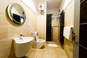 Enjoy a shower experience in this bathroom, featuring a standalone sink, compact toilet, and wall-mounted mirror.