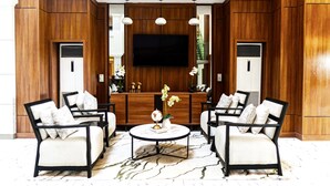A modern living room with two sofas, a coffee table, and a TV mounted on a wooden wall. - Summit Hotel and Apartments VGC (Lekki)