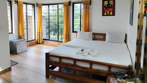 A bedroom with a wooden bed, a ceiling fan, and large windows with curtains. - Khoai Village Resort (Bolpur)