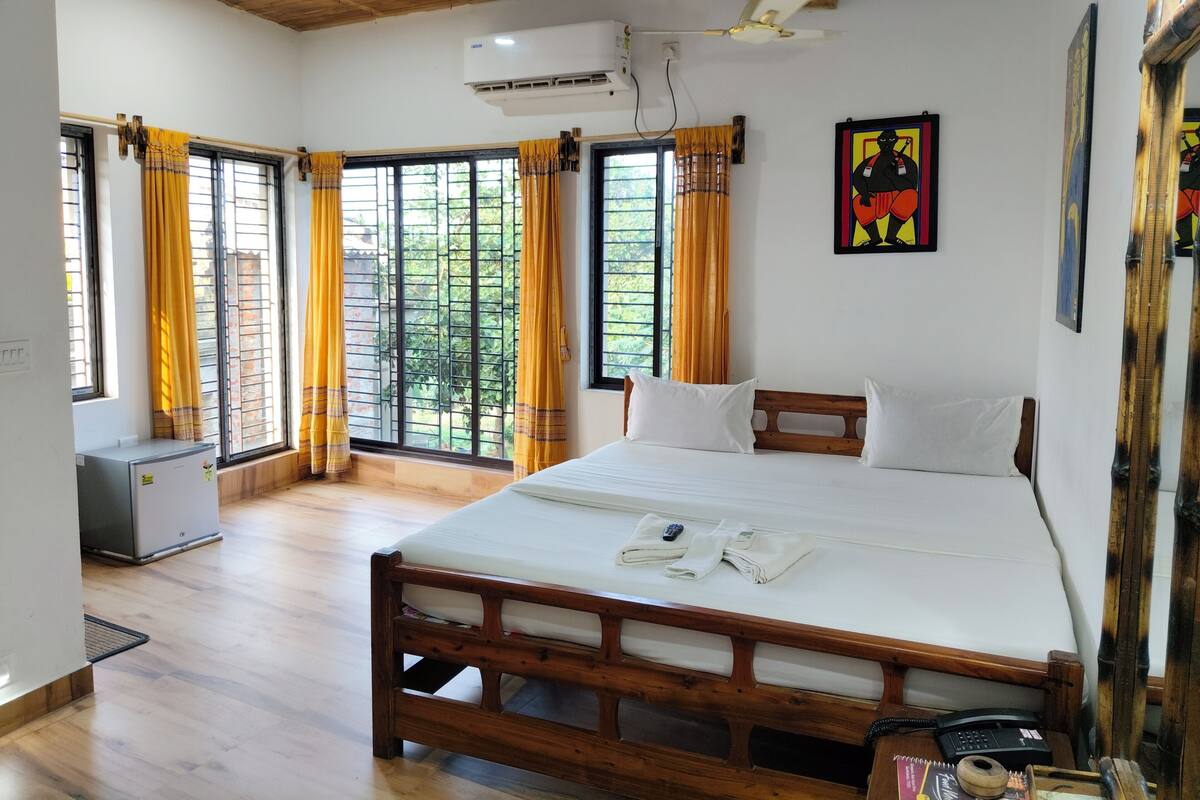 Un dormitorio con una cama de madera, un ventilador de techo y ventanas grandes con cortinas.