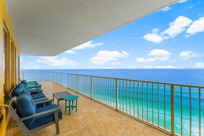 Ein Balkon mit Meerblick, ausgestattet mit einer Reihe blauer Sitzgelegenheiten und einem kleinen Tisch.