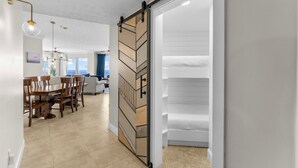 Un interior modern amb una porta corredissa de tipus graner que condueix a un dormitori amb llit i armari de color blanc.