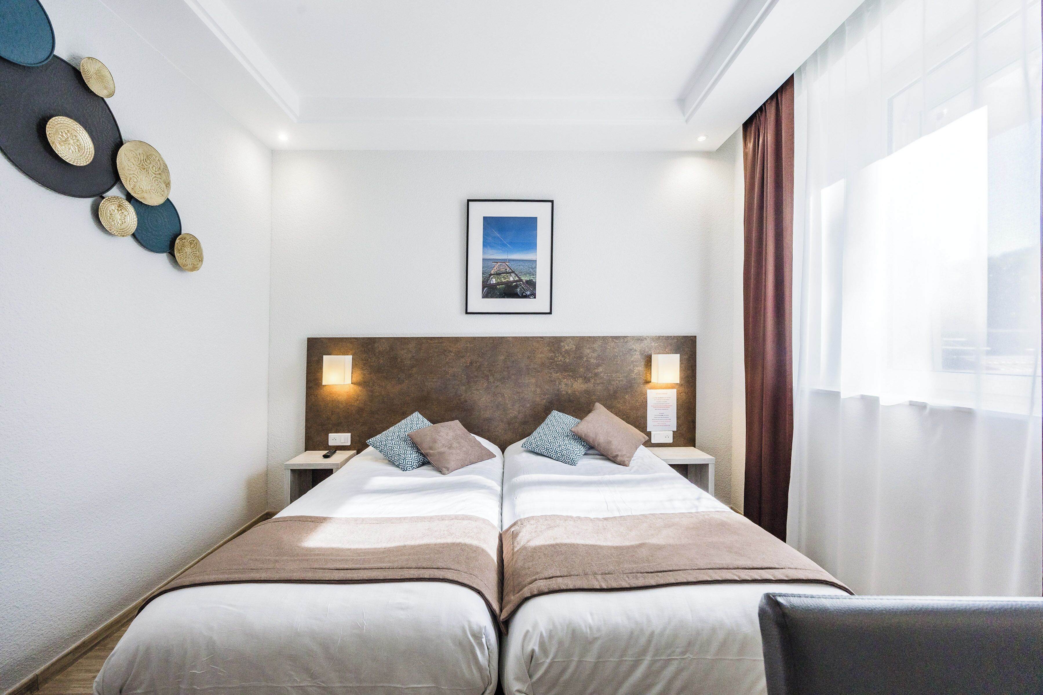 A double bed with a headboard, bedside lamps, a framed picture, and a view of the outdoors.