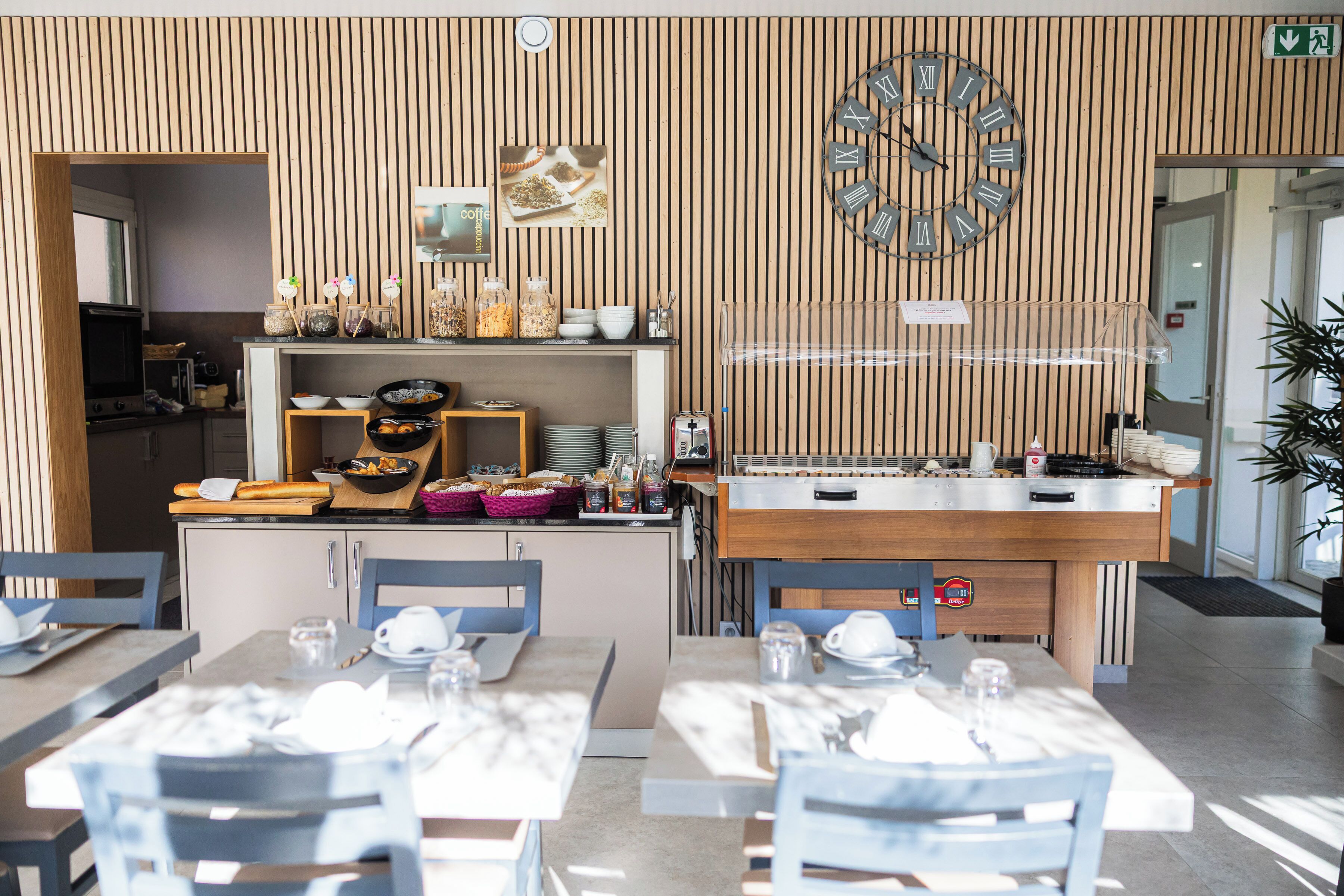 A modern dining area with a wooden panel wall, a clock, and a buffet counter.