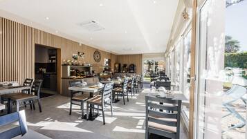 Um restaurante moderno com um amplo espaço de jantar, painéis de madeira em uma parede e grandes janelas.