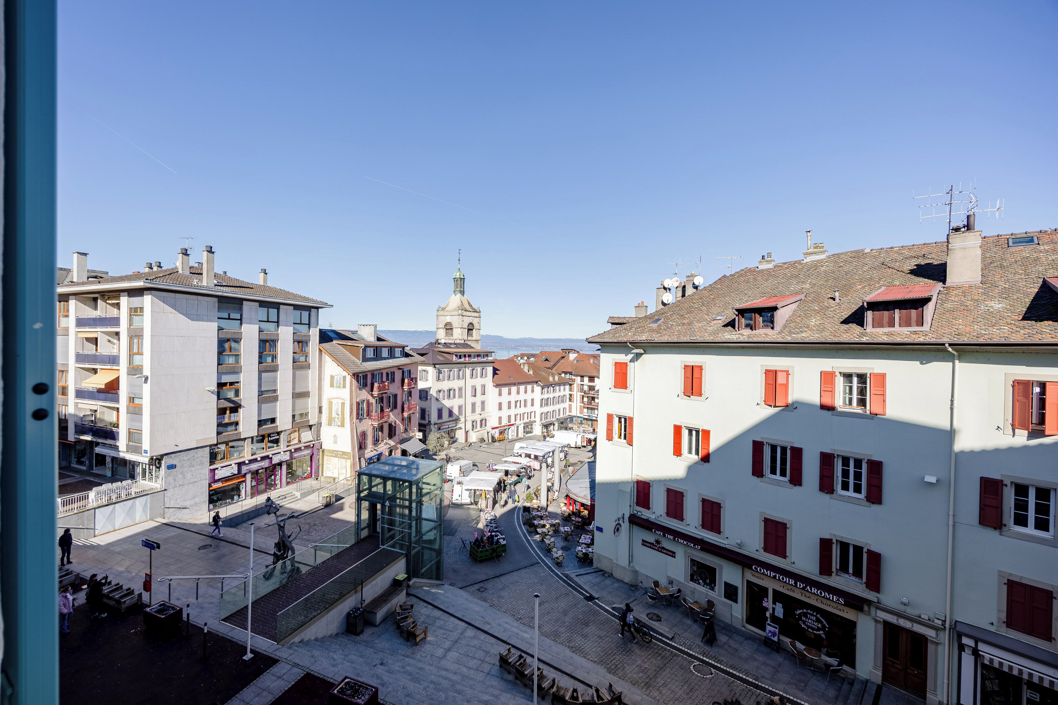A street view with buildings, a dome structure, and outdoor seating areas.