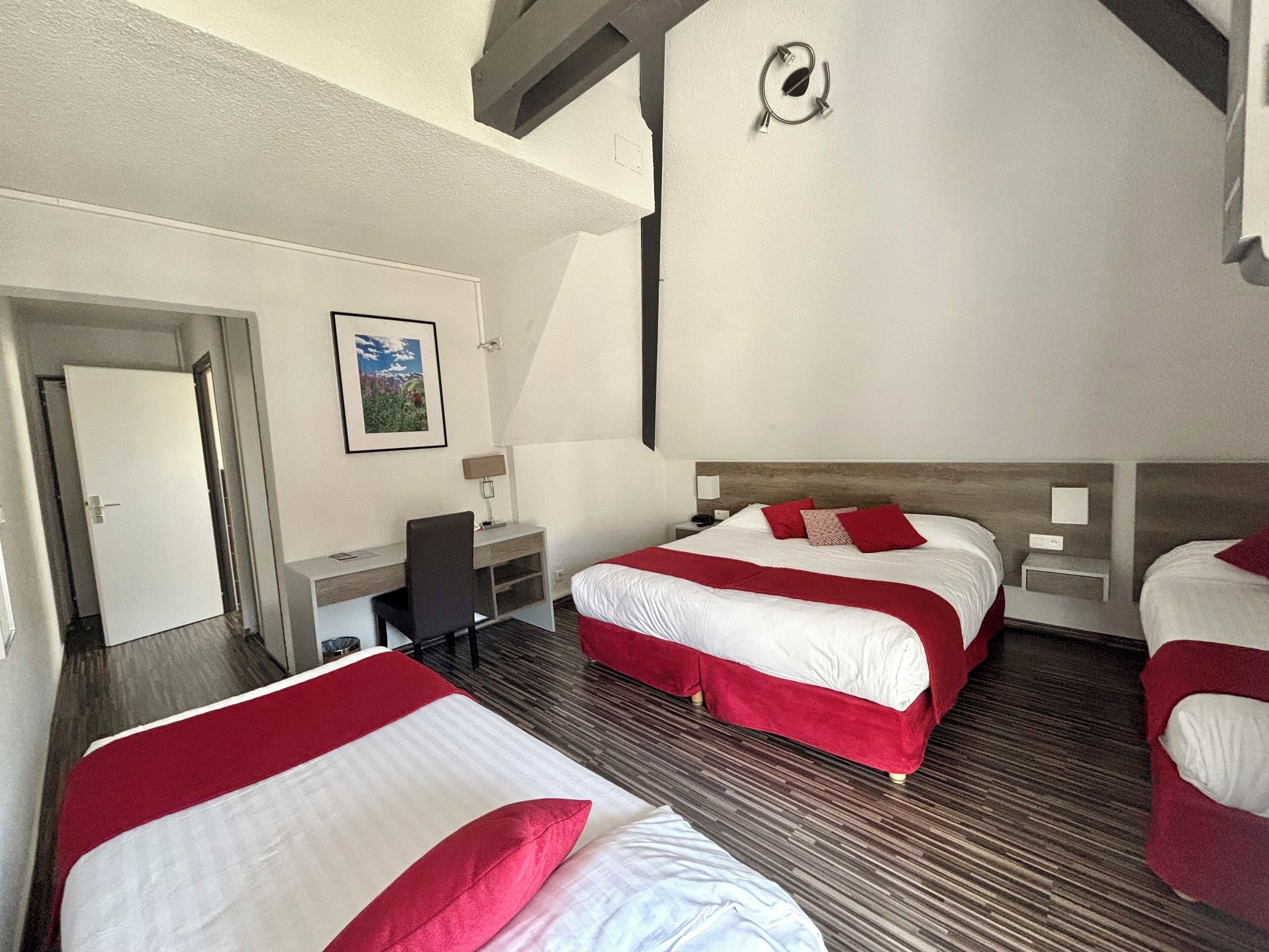 A hotel room with two beds, a desk, and a chair.