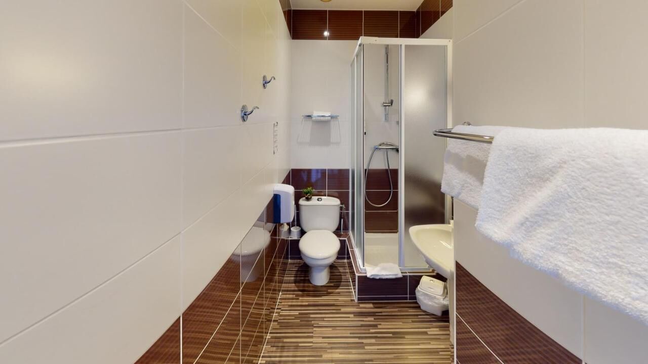 Ein modernes Badezimmer mit Dusche, Toilette und Waschbecken, mit gestreiftem Boden und weißen Wänden.