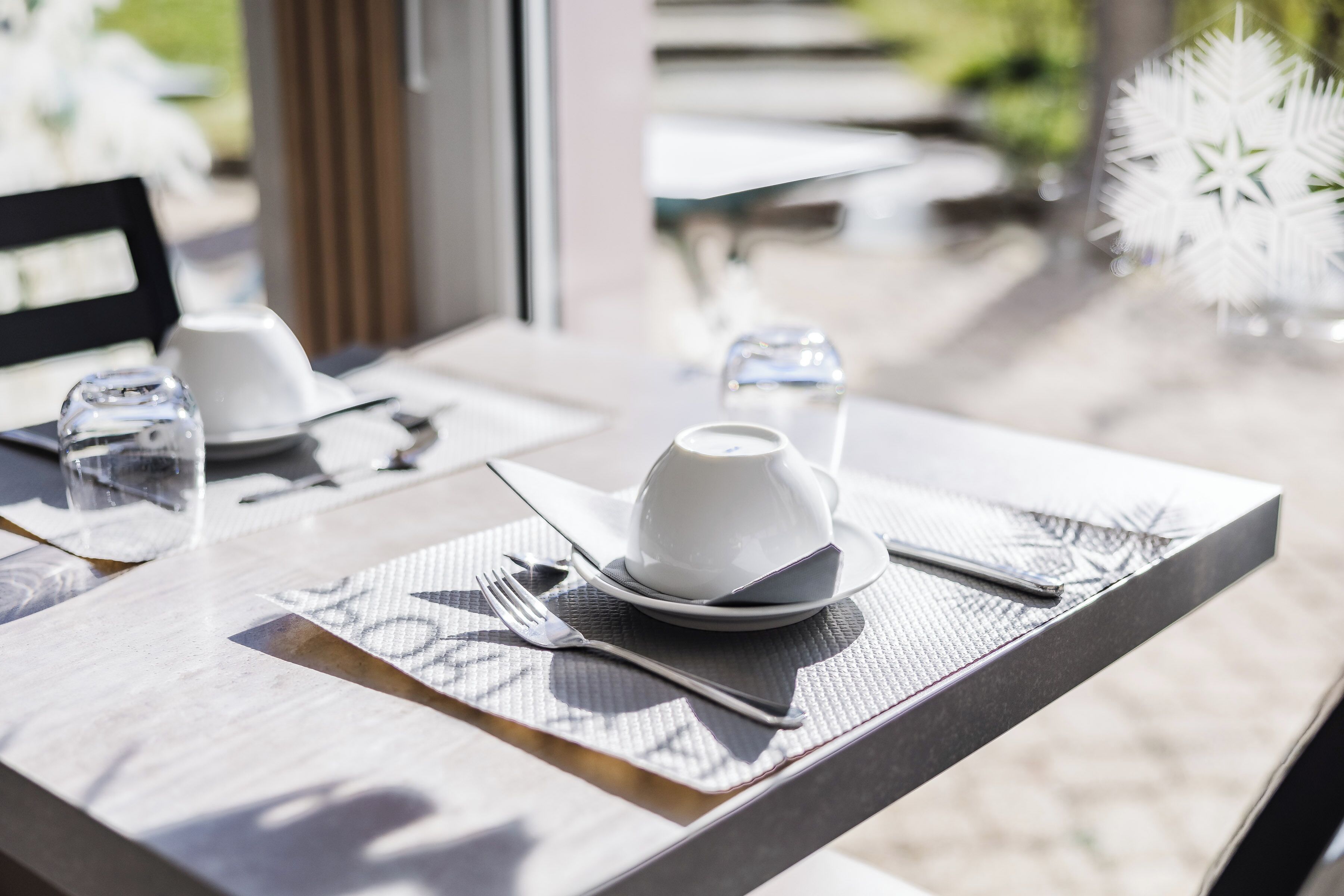 A dining table set with a white cup, saucer, plate, fork, and knife.