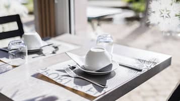 A dining table set with a white cup, saucer, plate, fork, and knife.