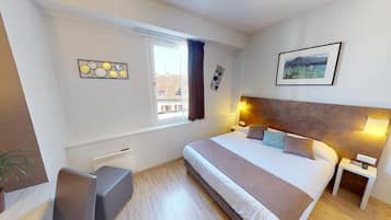 A modern hotel room with a large bed, bedside tables, a desk, and a window with curtains.