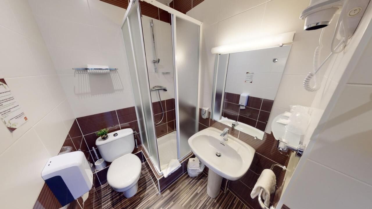 A modern bathroom with a glass shower enclosure, a toilet, a sink, and a mirror.