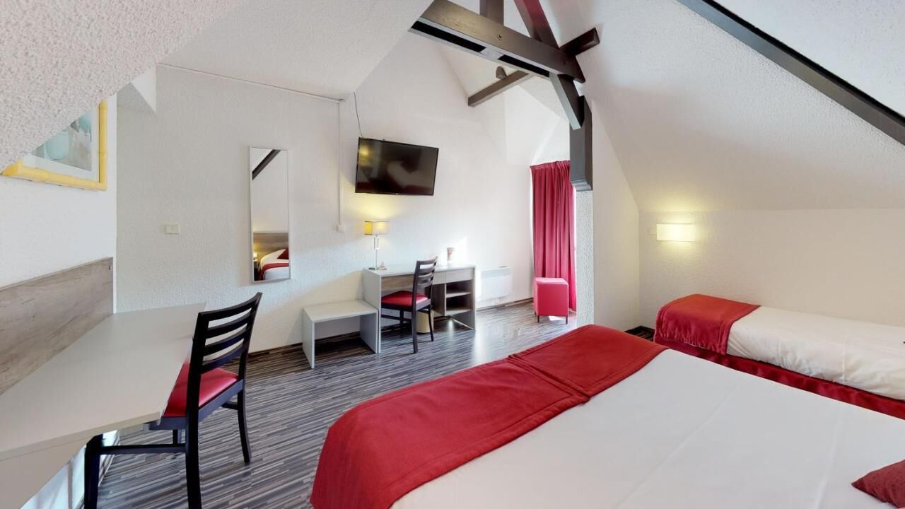 A bedroom with a bed, a desk, and a chair.