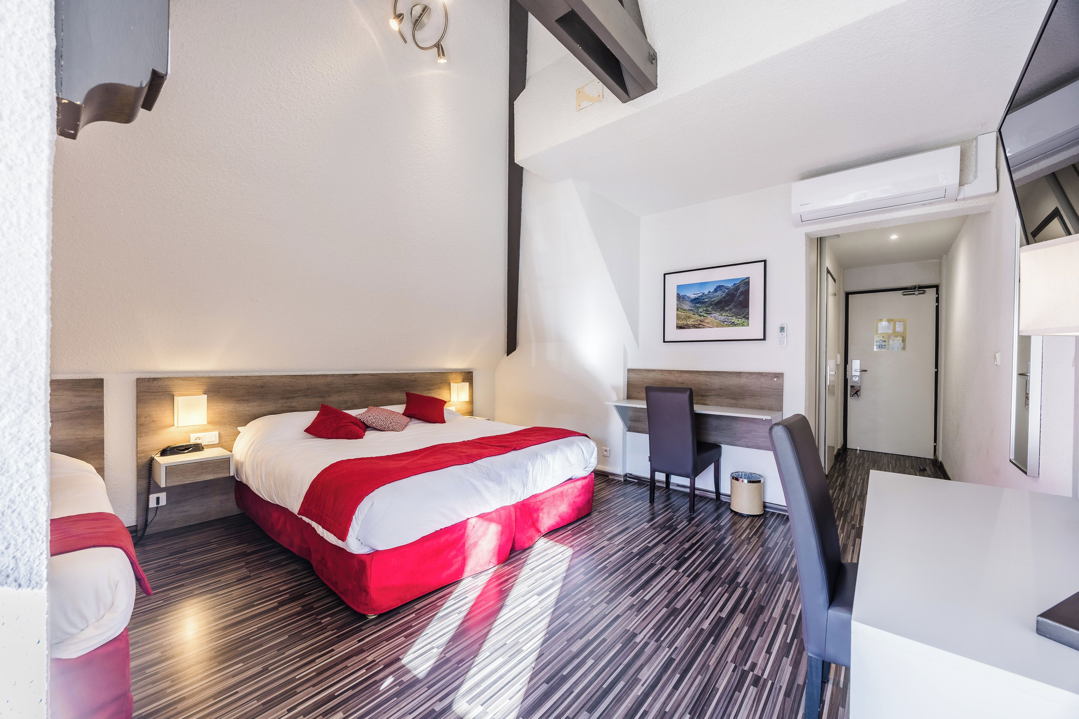 A hotel room with a bed, bedside tables, a desk, and a chair.