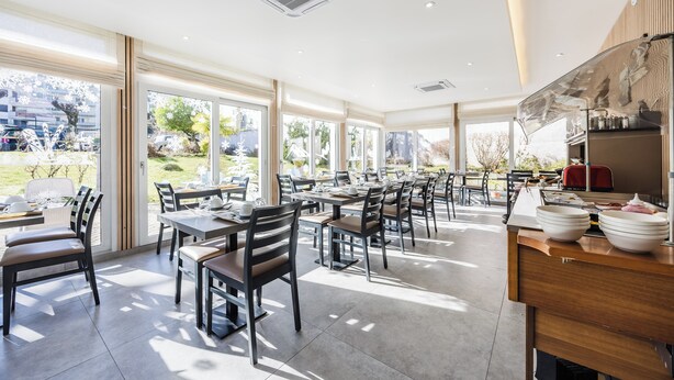 Un comedor amplio con mesas y sillas, ventanas grandes y vistas al exterior.