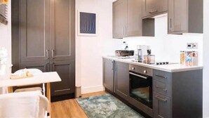 A modern kitchen with dark cabinets, a white countertop, and a built-in oven. - Designer Flat in Heart of Brighton - Walk to Beach & Attractions! (Brighton and Hove)