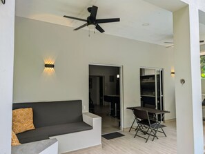 A modern living room with a dark grey sofa, a small table, and a ceiling fan.